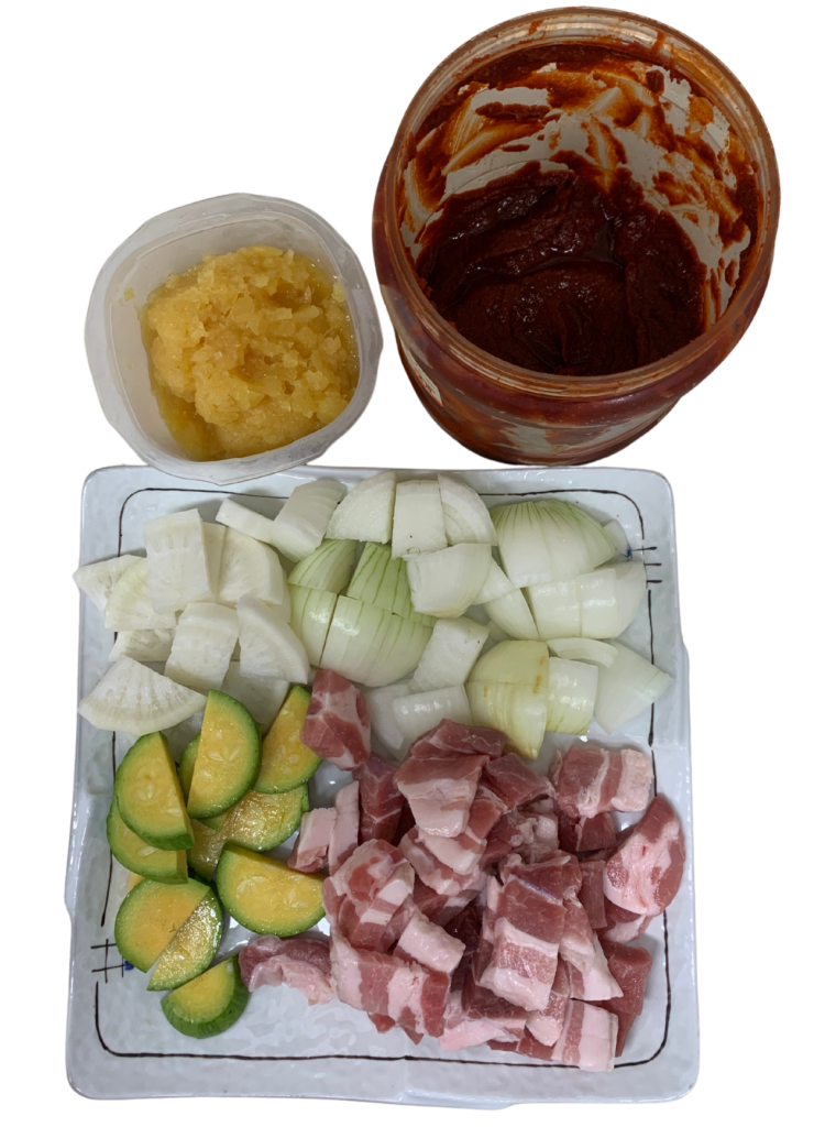 고추장찌개에 사용될 깍둑썰기 된 돼지고기, 무, 양파, 애호박과 고추장, 다진 마늘이 정갈하게 준비된 모습