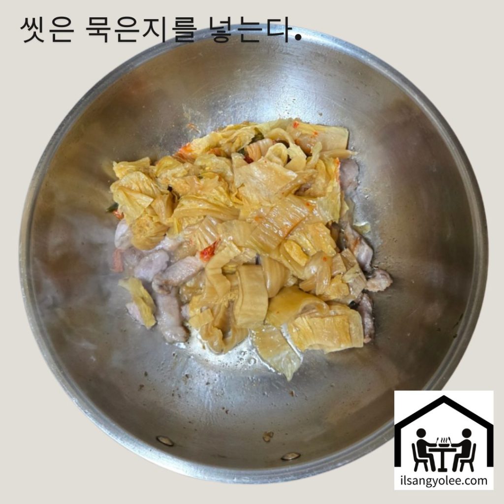 볶아진 돼지고기 위에 묵은지를 넣고 함께 볶는 모습
