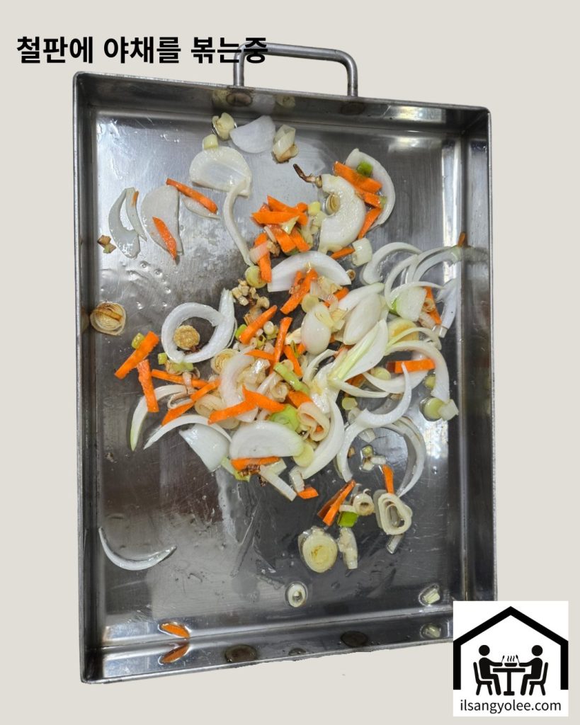 철판 위에서 파기름을 내며 볶아지는 대파, 양파, 당근