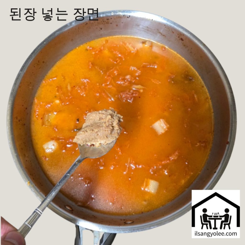 끓고 있는 김치찌개에 된장을 한 스푼 넣는 모습