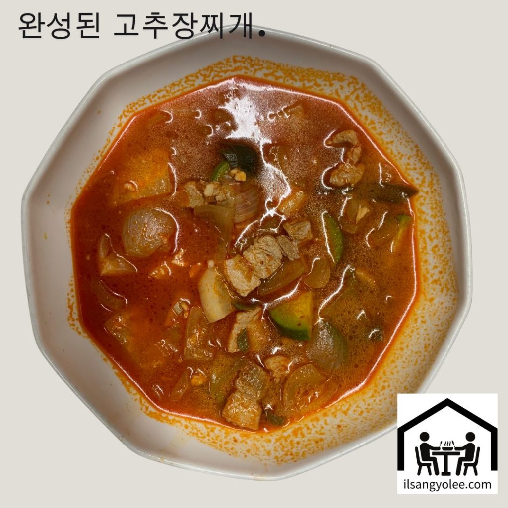 완성된 돼지고기 고추장찌개가 하얀 볼에 담겨져 있는 모습. 붉은 국물과 건더기가 먹음직스럽다.
