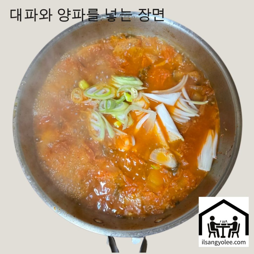 끓는 김치찌개에 썰어둔 대파, 양파를 넣는 모습